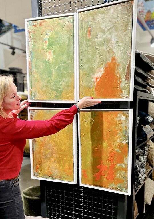 Abstract mixed media artwork with vibrant green, orange, and gold hues, textures evoking surrealism, fluid movements, and delicate contrasts held up by a woman in a red shirt. Artwork style is Abstrakt and technique Mixed Media.