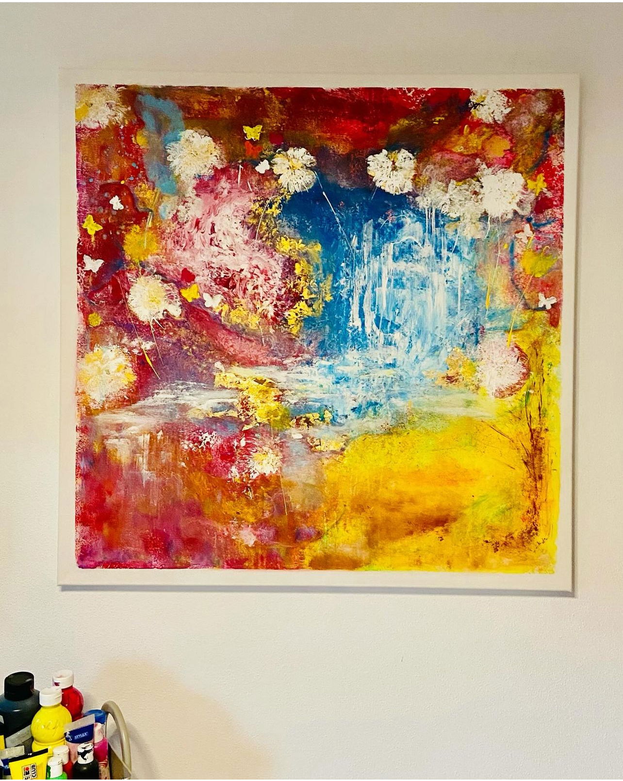 A vibrant mixed media artwork with abstract interplay of crimson, azure, and golden hues, textured butterflies, and ethereal dandelions evoking whimsy and serenity. Artwork style is Akstrakt and technique Mixed Media.